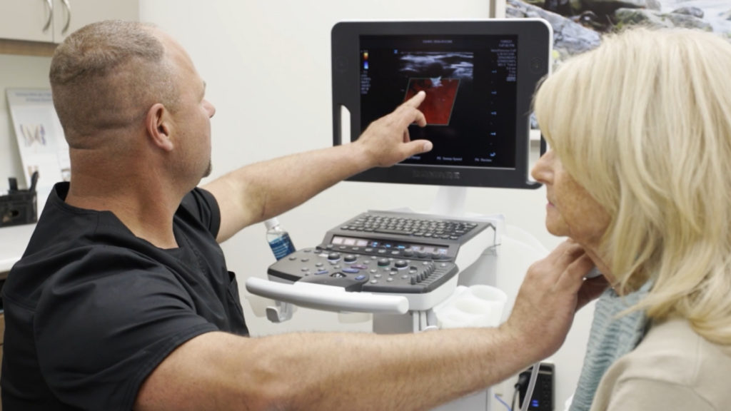 vascular surgeon during a consultation reviewing imaging with a patient