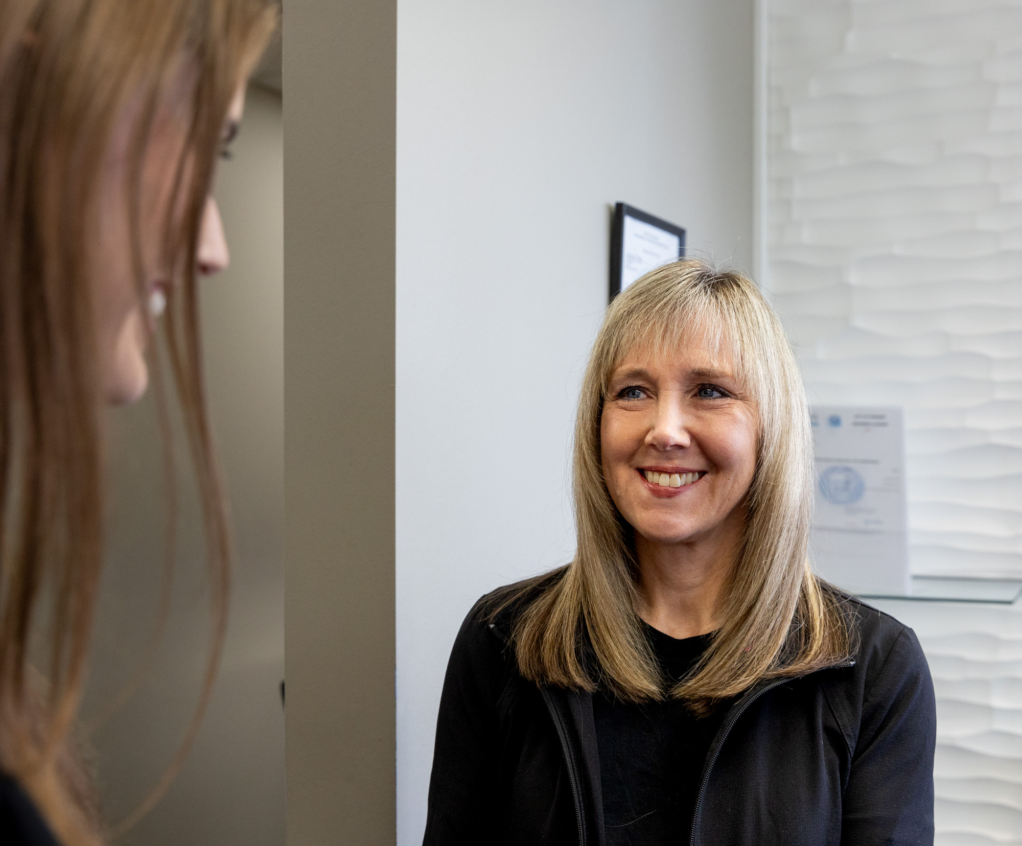 A patient with shoulder-length hair smiles as she learns about PRP for knee pain near Bentonville, AR.