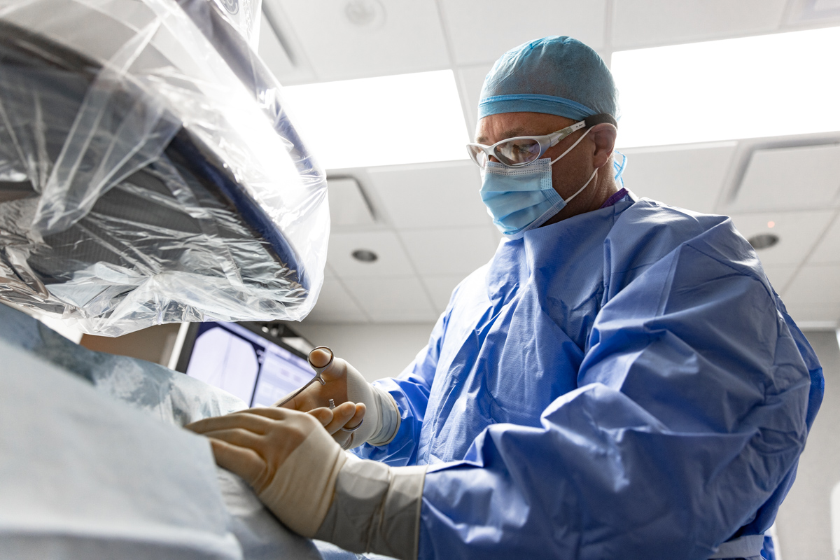 A surgeon in scrubs with a face mask performs a neuropathy treatment near Fayetteville, AR.